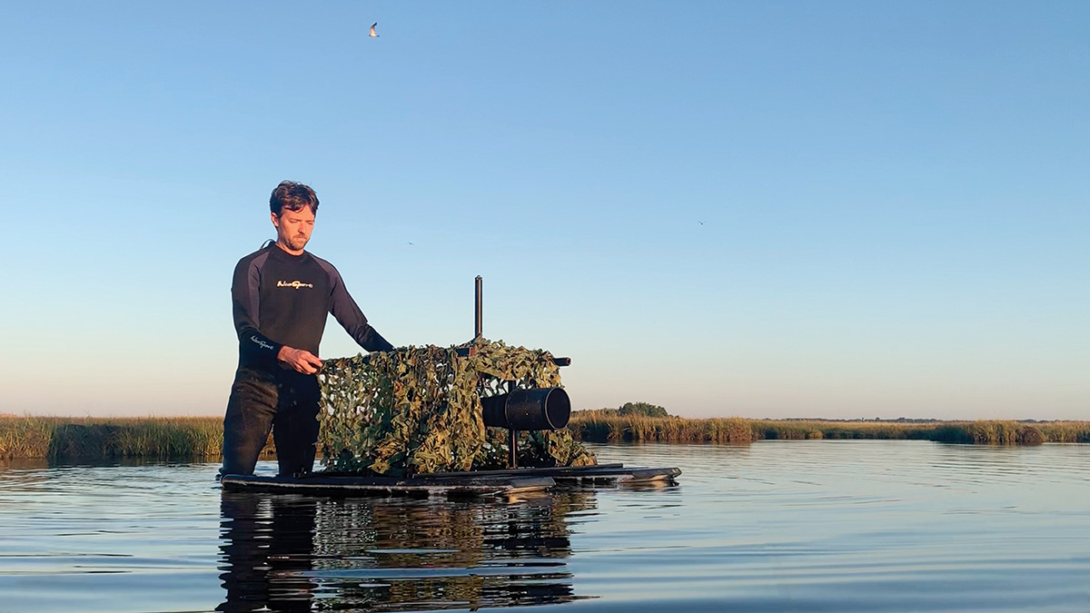 photographer Ray Hennessy standing in water holding his photography blind