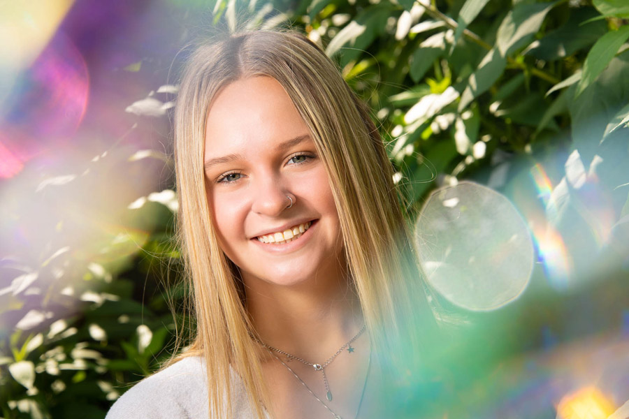 Portrait of a young person using Lensbaby Omni filters that create a color tinted flare