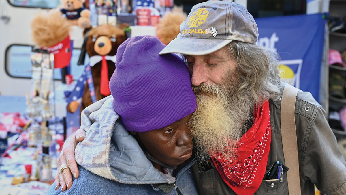 White man in hat hugs a Black woman wearing a purple knit hat after praying with her before pro-Trump demonstration at the State Capitol Building in Atlanta, Georgia, Nov. 21, 2020. 