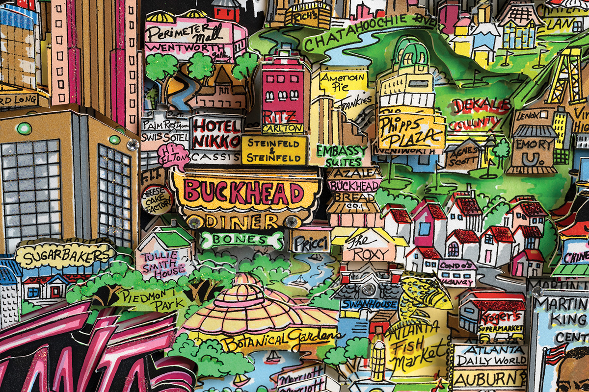 A hand-drawn illustration and paper sculpture map of Atlanta landmarks, businesses, and universities.