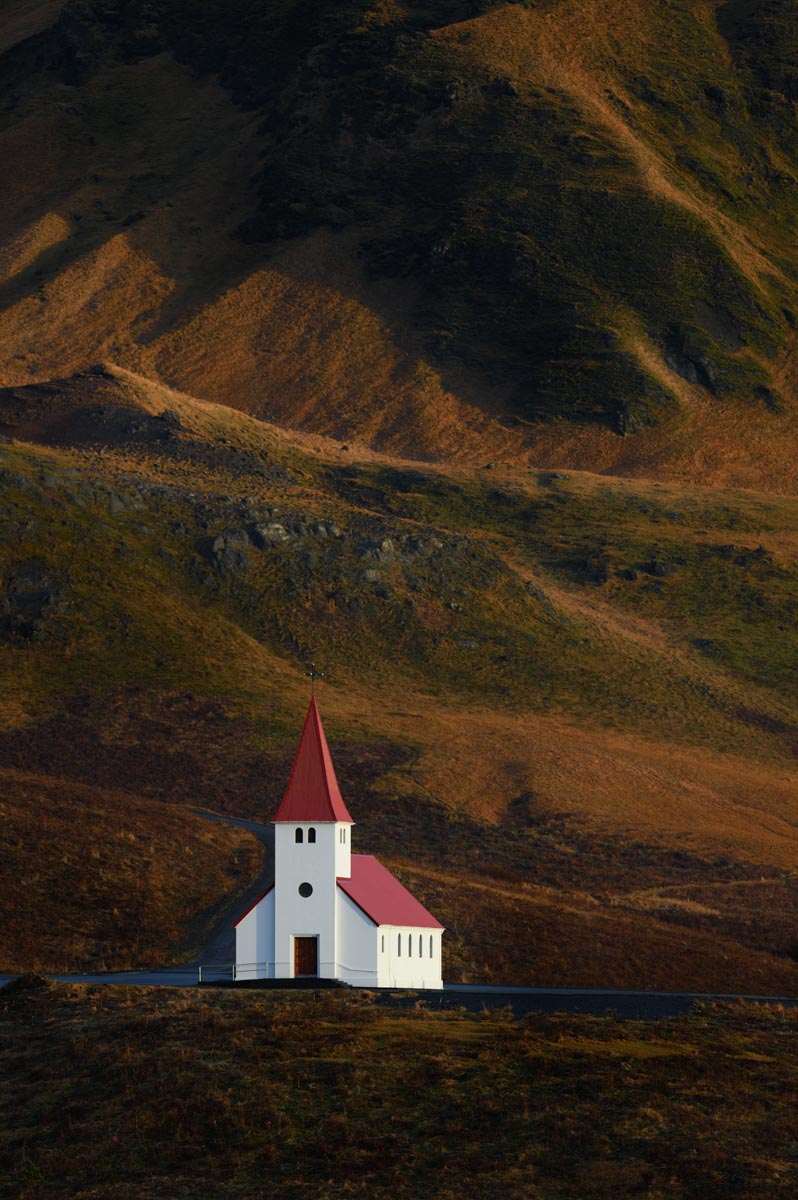 church with red steeple in front of fell
