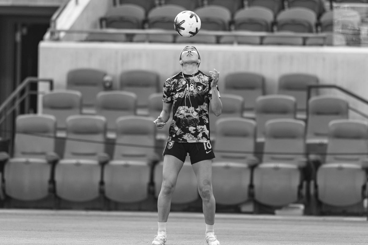 Angel City FC player Jun Endo juggling the ball while wearing headphones before a match