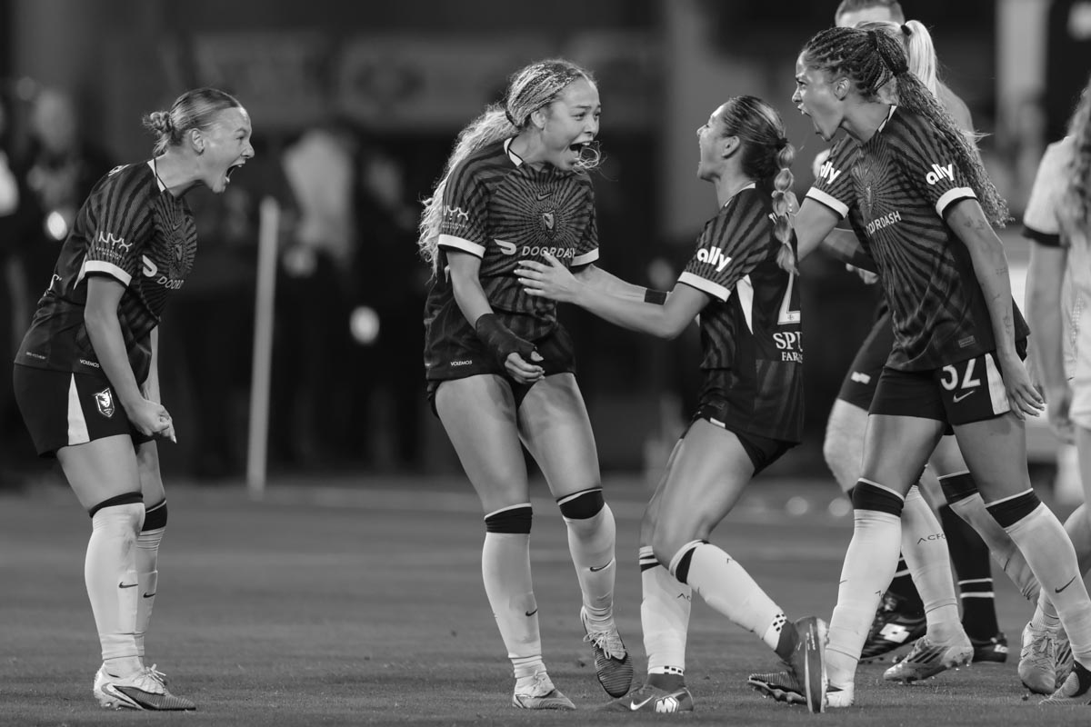 Angel City FC players screaming and smiling at each other during a match