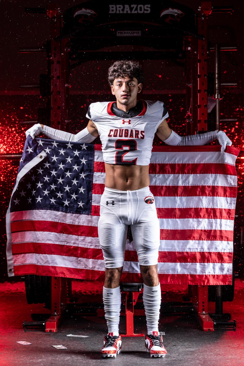 a high school football player holding up an American flag