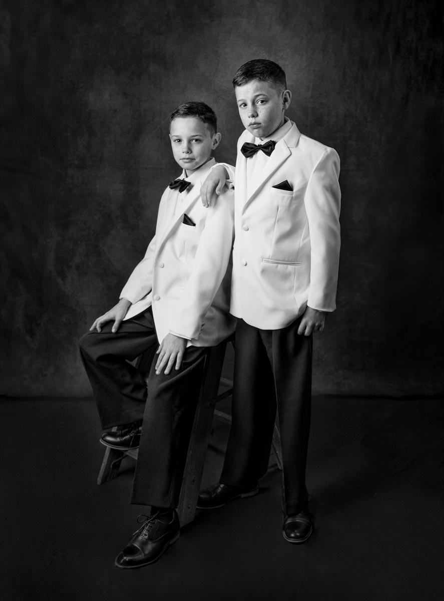 black-and-white portrait of two young boys wearing white tuxedo jackets