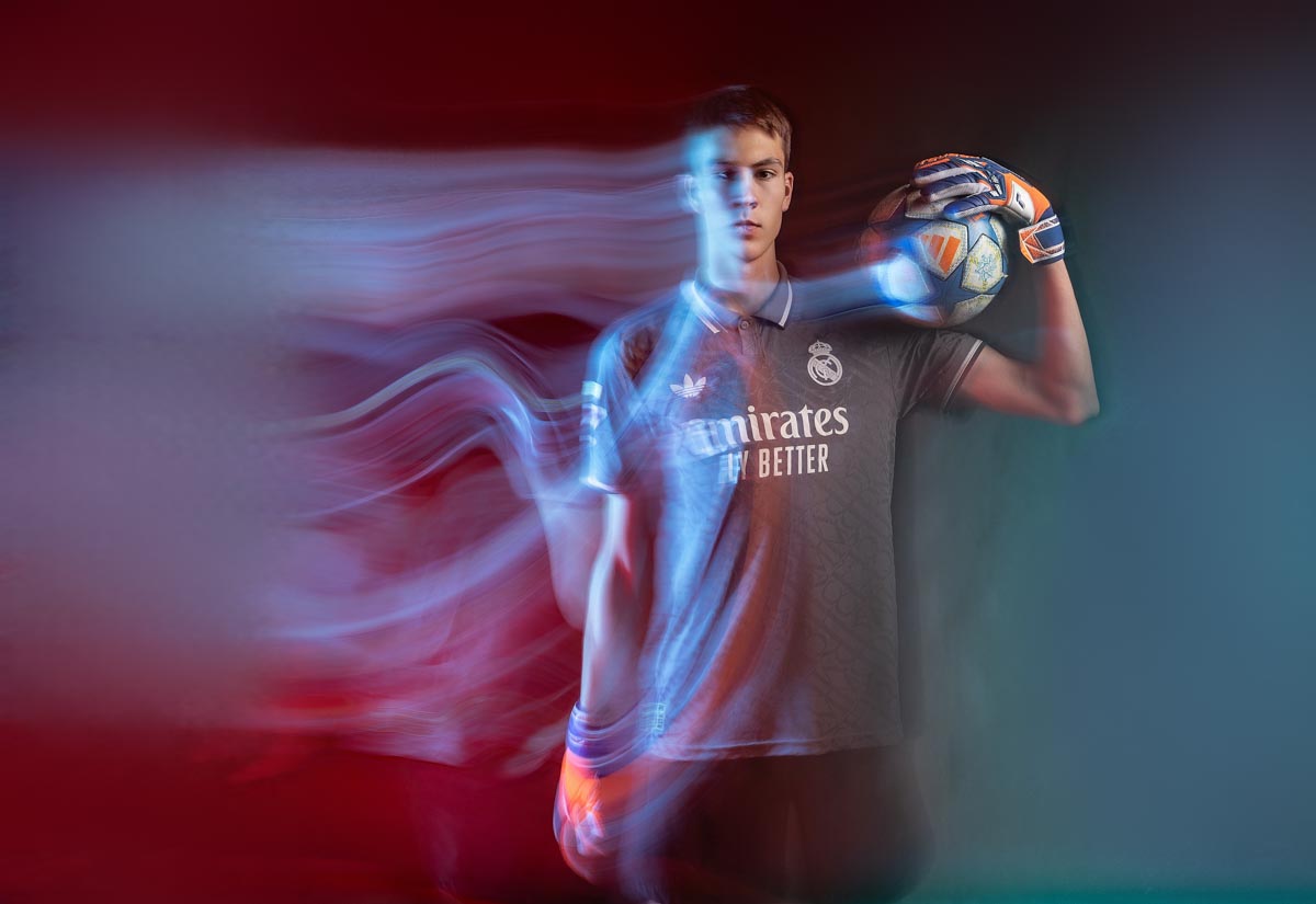 light painting image of a teenage boy holding a soccer ball with half of his body blurred into wavy lines on the left side of the photo 