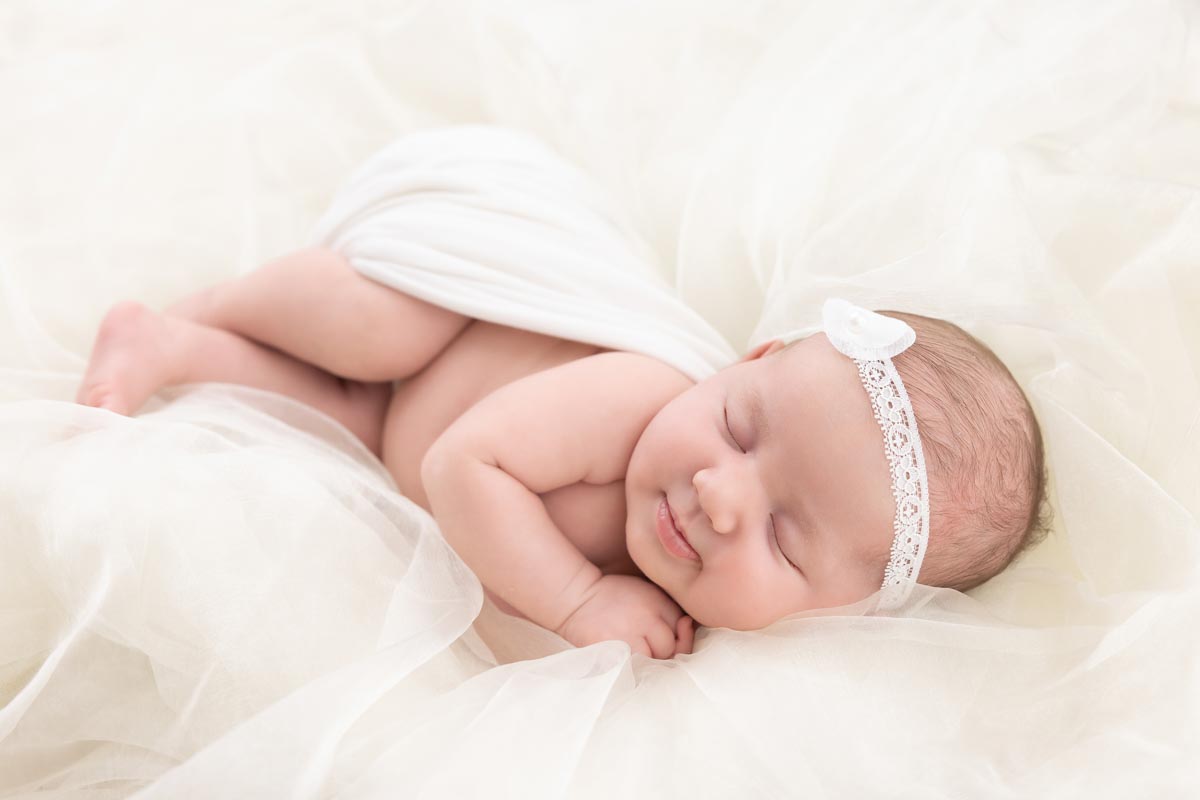 newborn asleep on white tulle fabric