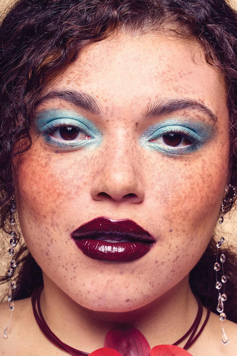 closeup portrait of a woman wearing blue eyeshadow and dark maroon lipstick