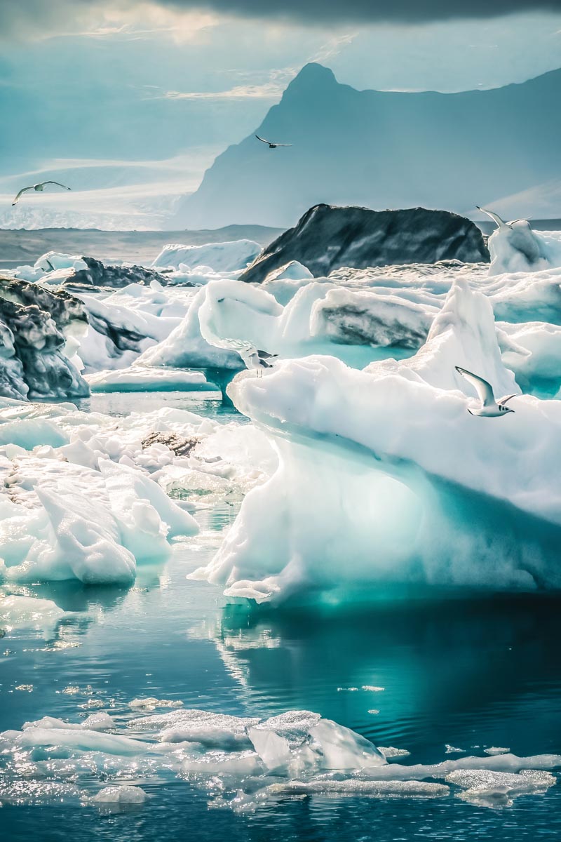 iceberg with rocks and mountain in background