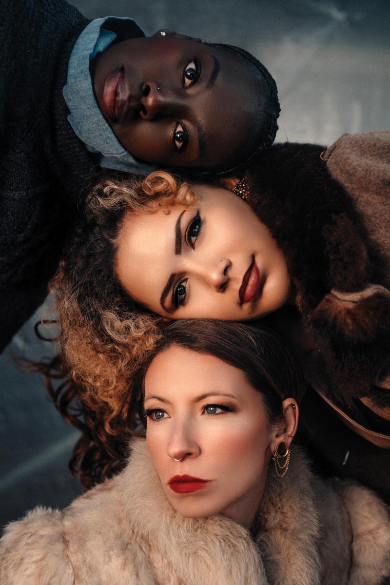three people lying with their heads together