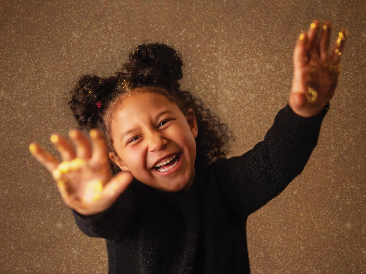 a young girl smiling and reaching toward the camera