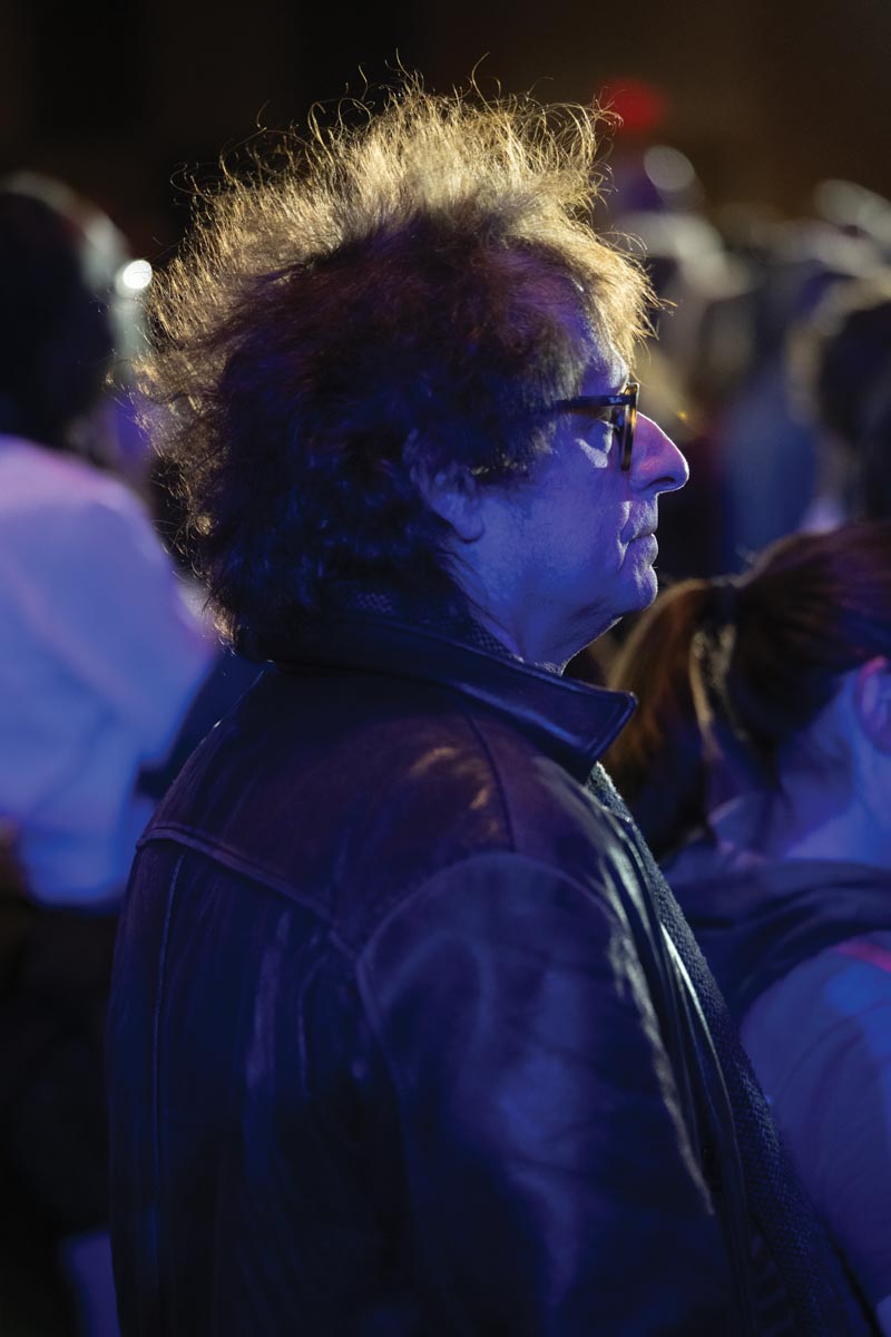 An audience spectator watching a musical performance in dim blue light