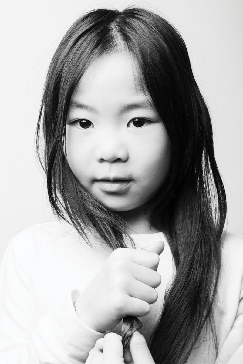 black-and-white portrait of a child who is holding her long hair in her hands