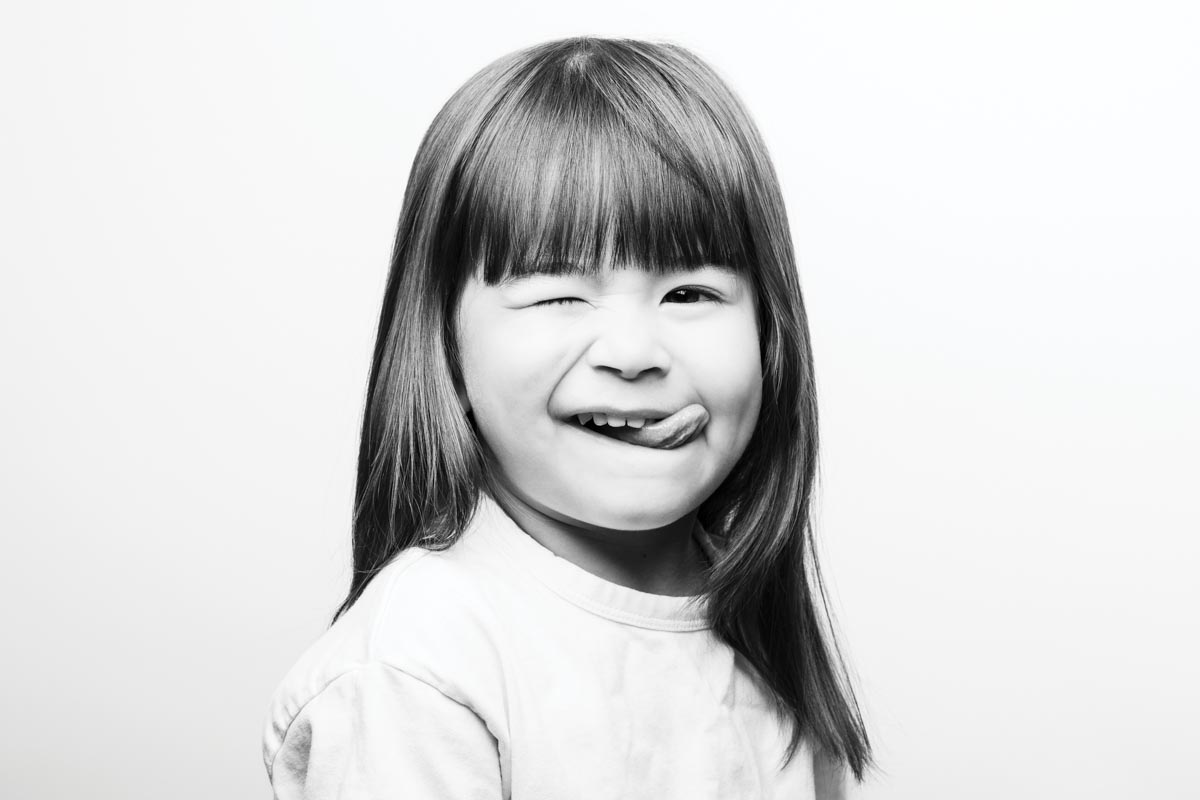 black-and-white portrait of a child sticking our her tongue