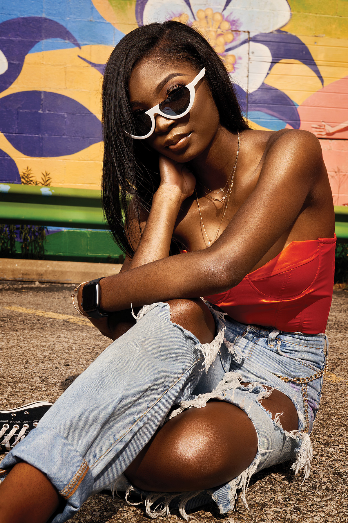 High school senior girl wearing sunglasses, red top and jeans