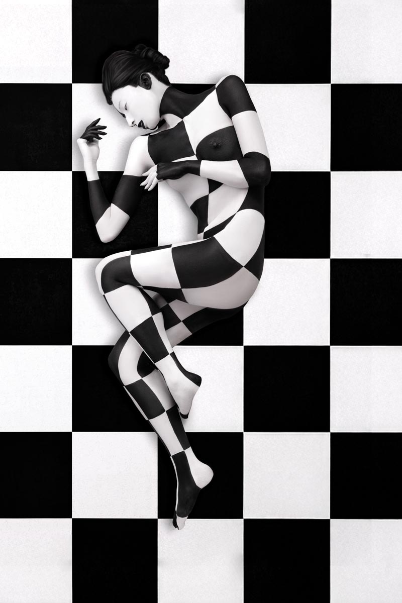 model painted in black and white checkers lying on a black and white checkered floor