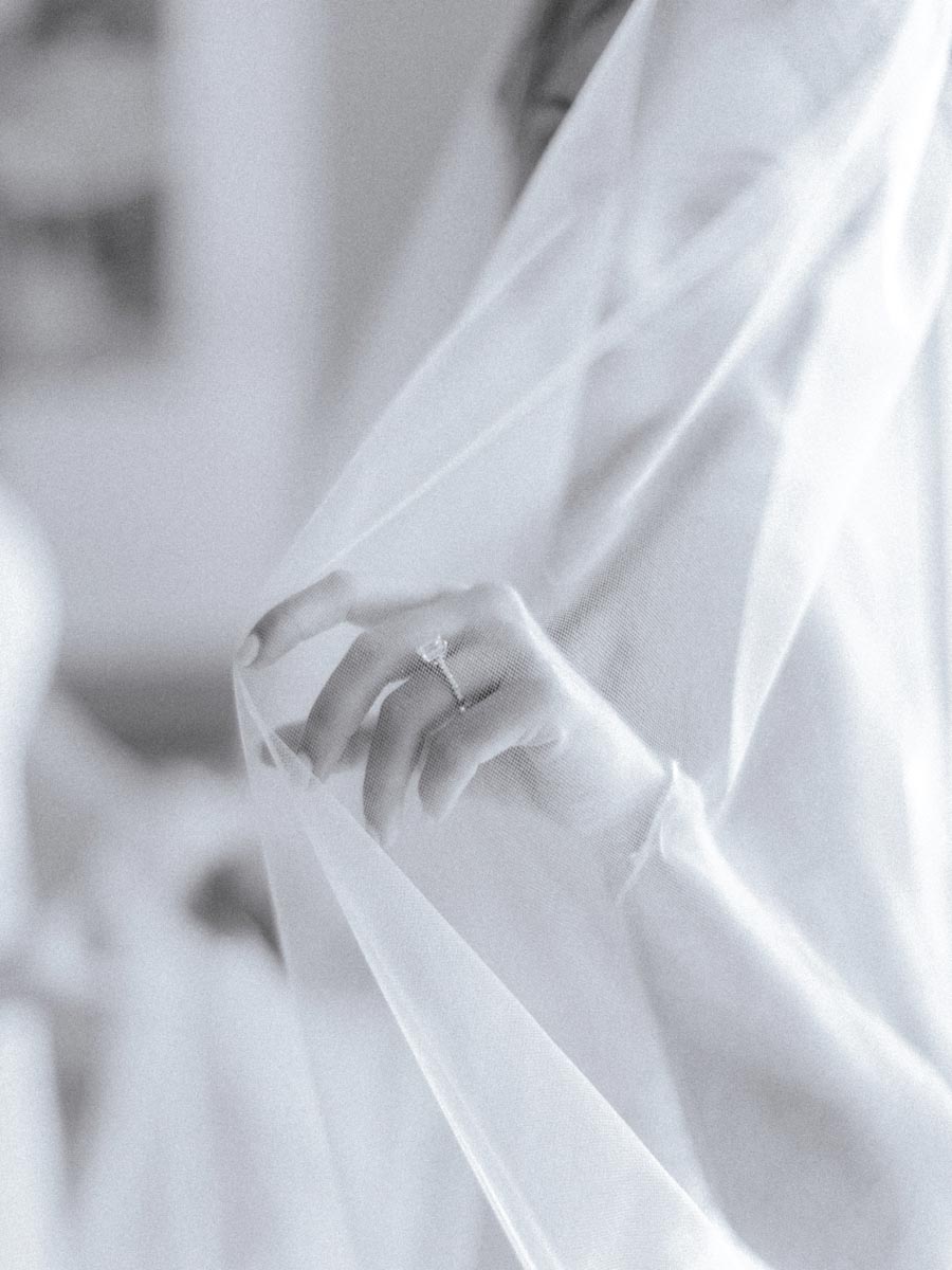 closeup of bride's hand with wedding ring underneath her veil