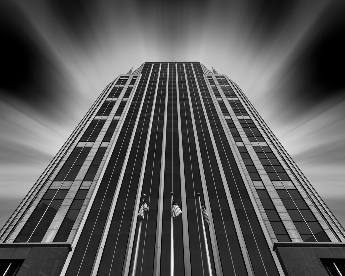 black and white photo of a skyscraper and sky from a low angle