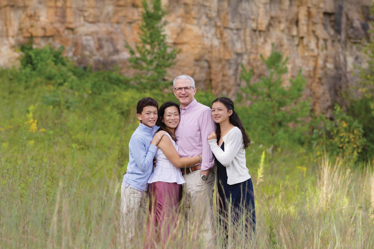 photo of parents and teenaged children in natural setting with tall grass and red rock formation in the background