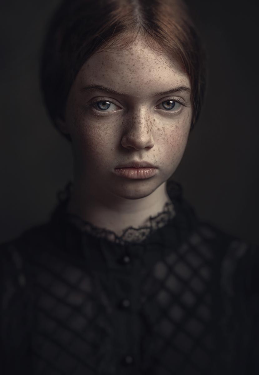 Sveta Butko's portrait of a young girl wearing a black dress on a dark backgroun