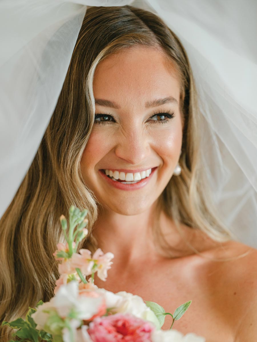 close-up photo of bride smiling with veil and bouquet