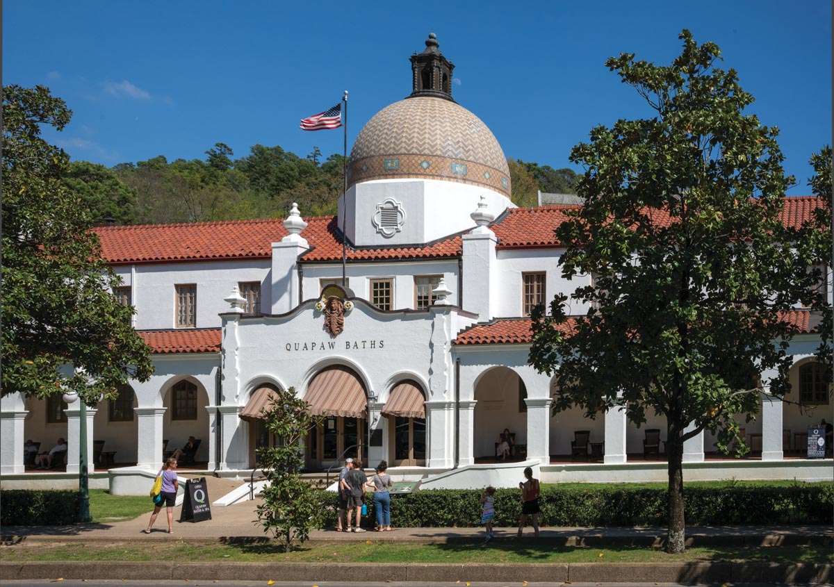 The front of a two-story bathhouse with a Spanish tile roof and covered walkway across the front