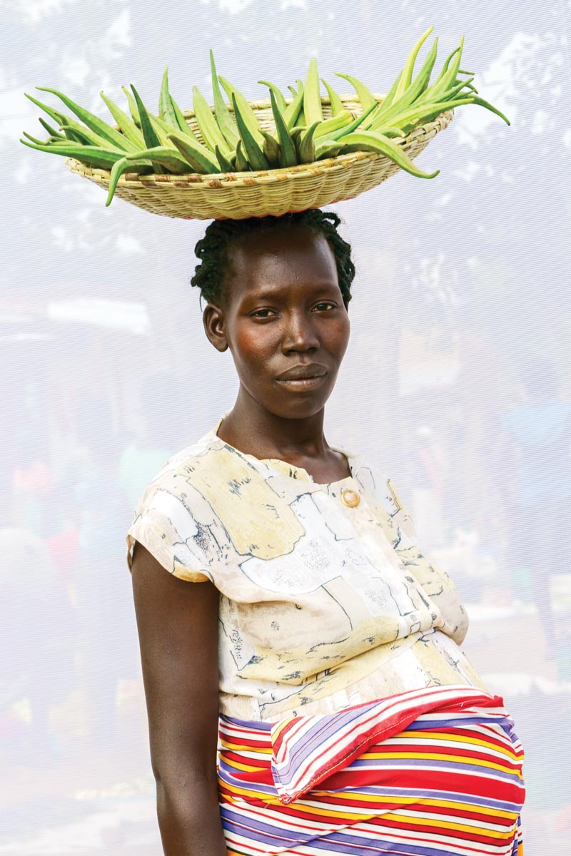 Dan Nelken portrait of a Ugandan woman with a basket full of produce balanced on her head